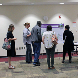 Attendees of a recent ONE VCU Master Plan open house gather around a poster board showcasing the Mobility and Safety guiding principle.